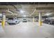 Spacious parking garage featuring multiple parking spaces, overhead lighting, and safety bollards at 7865 Vallagio Ln # 308, Englewood, CO 80112