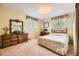 Bedroom with dual windows, wooden dresser with mirror, queen bed, desk and neutral decor at 1462 S Dudley St, Lakewood, CO 80232