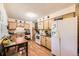 Functional kitchen with white appliances, wood cabinets, and adjacent dining area at 1462 S Dudley St, Lakewood, CO 80232