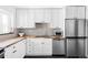 Bright kitchen with stainless steel appliances, white cabinets, stylish backsplash, and butcher block countertops at 1248 Ursula St, Aurora, CO 80011