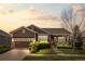 Charming ranch-style home with a well-manicured lawn, mature landscaping, and covered front porch at sunset at 21780 E Heritage Pkwy, Aurora, CO 80016