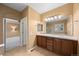 Well-lit bathroom with double sink vanity, large mirror, and adjacent bedroom access at 21780 E Heritage Pkwy, Aurora, CO 80016