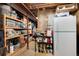 Unfinished basement with ample storage on wooden shelves and a white refrigerator at 49 Dawn Heath Cir, Littleton, CO 80127