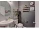 Stylish half bathroom featuring modern fixtures, decorative shelves, and a round mirror at 11158 Carbondale St, Firestone, CO 80504