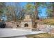 A custom outdoor stone fireplace sits on a concrete patio surrounded by mature trees and beautiful landscaping at 7957 Towhee Rd, Parker, CO 80134