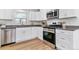 Bright kitchen featuring white cabinets, stainless steel appliances, gray counters, and wood-look floors at 2550 Kendall St, Edgewater, CO 80214