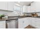 Bright kitchen featuring white cabinets, stainless steel dishwasher, and neutral countertop at 2550 Kendall St, Edgewater, CO 80214