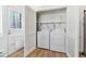 Laundry room featuring white washer and dryer, shelving, wood-look floors, and a door at 2550 Kendall St, Edgewater, CO 80214