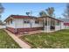 Backyard view of the home with a covered porch, and a white picket fence around the perimeter at 5294 S Prescott St, Littleton, CO 80120