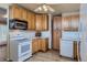Bright kitchen features wooden cabinets, white appliances, and a ceiling fan with lighting at 5294 S Prescott St, Littleton, CO 80120