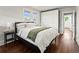 Airy bedroom with a black bed frame, white comforter, green throw, bedside table and windows at 3458 N Clayton St, Denver, CO 80205