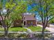 Charming brick home nestled behind mature trees, with a lush front lawn and driveway at 4434 Grove St, Denver, CO 80211