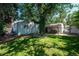 Spacious backyard with lush green lawn, mature trees offering ample shade, and a covered patio area at 2205 S King St, Denver, CO 80219