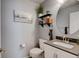 Stylish half bathroom with decorative shelves, round mirror, and modern fixtures at 7245 Prairie Cir, Longmont, CO 80504
