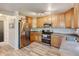 Well-lit kitchen with stainless steel appliances, wood cabinets, and wood-look floors at 7245 Prairie Cir, Longmont, CO 80504