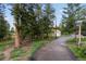 Long paved driveway leading to a detached garage surrounded by mature trees at 8701 Majestic View Dr, Conifer, CO 80433