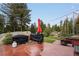 Outdoor patio with grilling area, red umbrella, and wooded surroundings at 8701 Majestic View Dr, Conifer, CO 80433