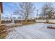 Snowy backyard with a tree, fence, and stone fireplace at 3780 Benton St, Wheat Ridge, CO 80212