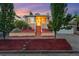 Inviting home with a manicured front yard, a brick facade, and a cozy porch, bathed in a colorful twilight at 1025 E Iowa Ave, Denver, CO 80210