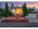 Charming brick home with landscaped front yard and steps leading to the front door at dusk at 1025 E Iowa Ave, Denver, CO 80210