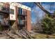 A brick apartment building with a balcony and exterior staircases, landscaped with grass and trees at 5995 W Hampden Ave # 17C, Denver, CO 80227