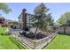 Landscaped backyard features a deck, a mature tree, and a fenced garden area at 7877 W 110Th Dr, Westminster, CO 80021