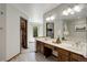 Bathroom featuring dual sinks, wood cabinets, and a view into the bedroom at 7877 W 110Th Dr, Westminster, CO 80021