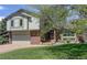 Charming two-story home with brick and siding exterior, manicured lawn, and mature trees at 7877 W 110Th Dr, Westminster, CO 80021