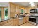 Bright kitchen featuring custom wood cabinets, granite counters, tile backsplash, stainless appliances, and a window over the sink at 7877 W 110Th Dr, Westminster, CO 80021