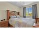 Comfortable bedroom has a wooden headboard, a patterned bedspread, and a window with sheer curtains at 20928 E Hamilton Ave, Aurora, CO 80013