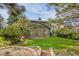 View of the expansive backyard with lush lawn, mature trees, and a charming brick-lined garden at 7655 S Olive Cir, Centennial, CO 80112