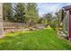 Lush green backyard featuring a well-manicured lawn, tiered garden beds, and mature trees for privacy at 7655 S Olive Cir, Centennial, CO 80112