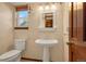 Classic powder room features pedestal sink, framed mirror, and decorative wallpaper, creating a cozy space at 7655 S Olive Cir, Centennial, CO 80112