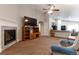 Cozy living room showcasing a fireplace, TV, ceiling fan, and open access to the kitchen at 5131 Delphinium Cir, Brighton, CO 80601