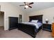 The main bedroom features a dark wood king bed, ceiling fan, and walk in closet at 5131 Delphinium Cir, Brighton, CO 80601