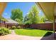 Secluded backyard features a well-manicured lawn, brick patio, and a privacy fence surrounded by mature trees at 6600 E 4Th Ave, Denver, CO 80220