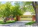 Charming brick home featuring an attached garage and a well-maintained front yard with mature trees at 6600 E 4Th Ave, Denver, CO 80220