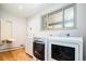 Well-lit laundry room boasts hardwood floors, modern washer/dryer, and built-in ironing board at 6600 E 4Th Ave, Denver, CO 80220