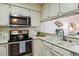 Bright kitchen featuring stainless steel appliances, white cabinets, and a serving counter at 7420 E Quincy Ave # 304, Denver, CO 80237
