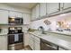 Bright kitchen with stainless steel appliances, white cabinets, and an adjacent living space at 7420 E Quincy Ave # 304, Denver, CO 80237