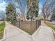 Home exterior featuring a grassy yard, mature trees, black metal fencing and sidewalk at 755 S Milwaukee St, Denver, CO 80209