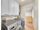 This laundry room features modern washer and dryer, white cabinets for storage and access to another room at 755 S Milwaukee St, Denver, CO 80209