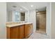 This bathroom features a tiled walk-in shower, a wooden vanity, and a large mirror at 11715 W 30Th Pl, Lakewood, CO 80215