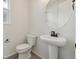 Simple yet elegant half bathroom with pedestal sink and round mirror at 9204 Truckee Ct, Commerce City, CO 80022