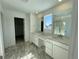 Well-lit bathroom featuring double vanities, marble floors, white cabinets, and a glass-enclosed shower, exuding modern elegance at 5546 Inland Ave, Firestone, CO 80504