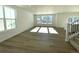 Spacious living room with wood floors, white walls, large windows, and a staircase leading to the upper floor at 5546 Inland Ave, Firestone, CO 80504