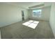 Bright main bedroom with a tray ceiling, carpet, and a large window; ensuite bathroom partially visible in background at 5546 Inland Ave, Firestone, CO 80504