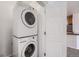 Efficient stacked washer and dryer beside a door with a peek into the kitchen area at 2705 S Danube Way # 110, Aurora, CO 80013