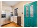 Compact kitchen with stainless steel refrigerator and an adjacent entryway with a teal door at 2646 Colorado Blvd, Denver, CO 80207