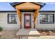 Close up of home's front door with natural wood entry covering, plants, and minimalist rock yard at 5362 S Cedar St, Littleton, CO 80120